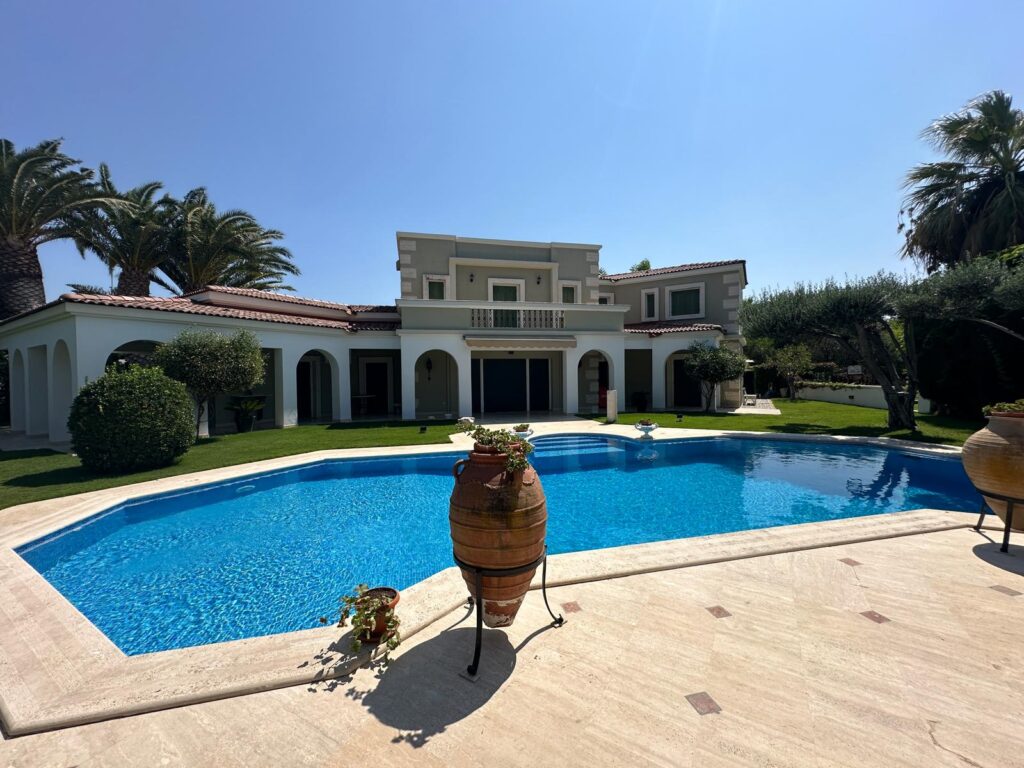 Çeşme Ilıca'daki Şantiye Evleri bölgesinde yer alan, klasik Ege mimarisine sahip lüks bir villa. Geniş turkuaz havuzu, beyaz kemerli verandalarıyla dikkat çeken yapının çevresinde palmiye ve zeytin ağaçları bulunuyor.